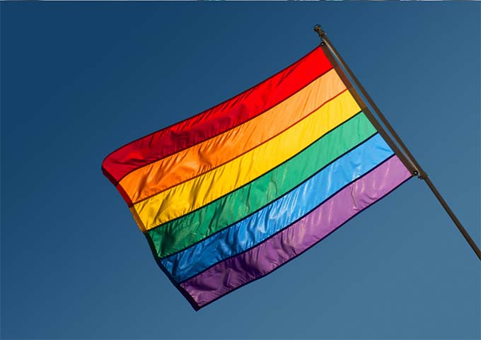 The LGBTQ+ pride flag on a blue sky